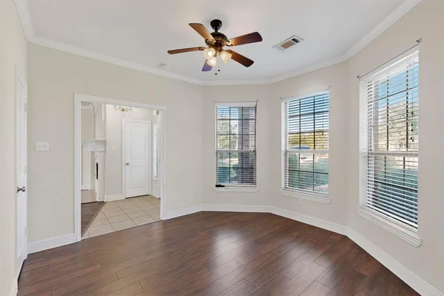 an empty room with wooden floor and ceiling fan