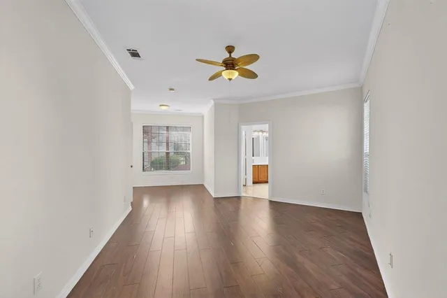 a view of an empty room with window and wooden floor