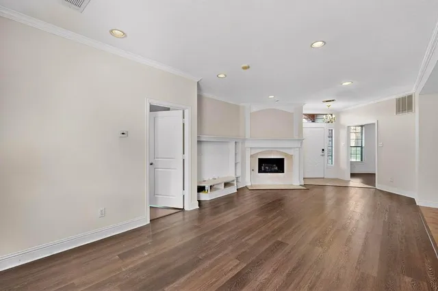 a view of an empty room with wooden floor fireplace and a window