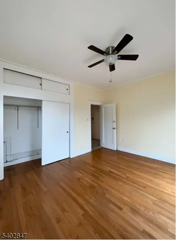 a view of empty room with wooden floor and ceiling fan