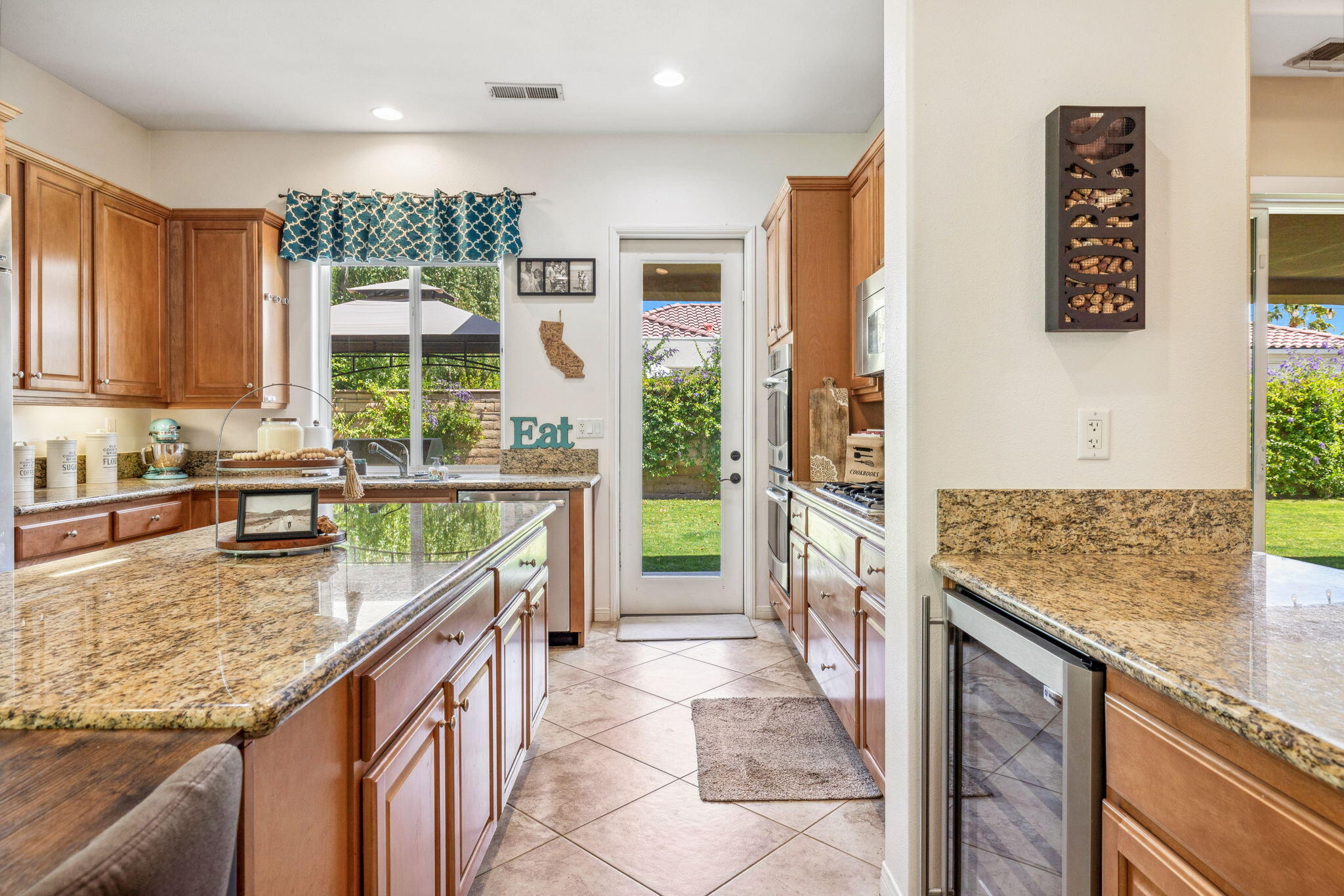 79040 Shadow Trail La Quinta, CA 92253 - Photo 32 of 69 a kitchen with kitchen island granite countertop a sink a stove and a wooden cabinets