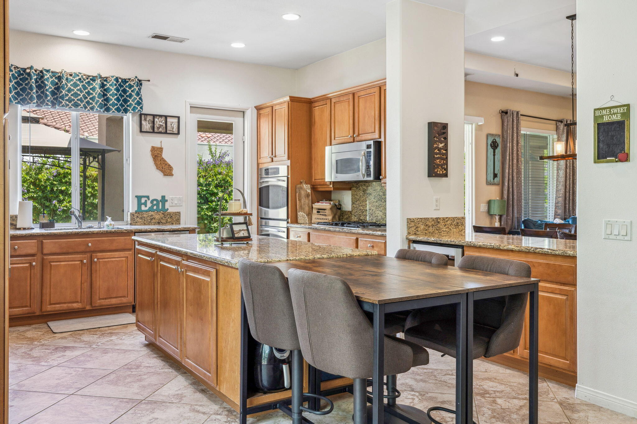 79040 Shadow Trail La Quinta, CA 92253 - Photo 33 of 69 a kitchen with granite countertop a table chairs sink and wooden cabinets