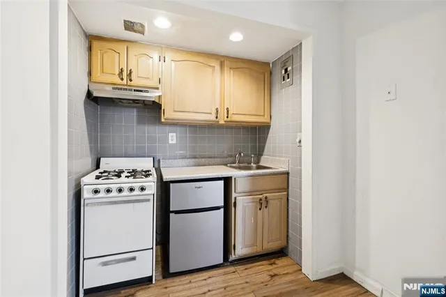 a kitchen with granite countertop cabinets stainless steel appliances and a wooden floor