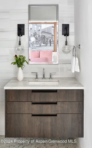 a bathroom with a sink a mirror and a potted plant