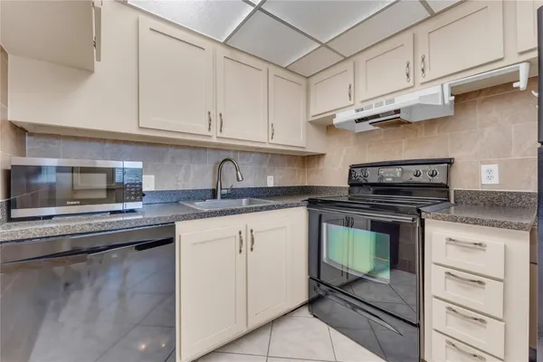 a kitchen with stainless steel appliances granite countertop a refrigerator and a stove top oven