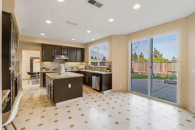 a kitchen with stainless steel appliances kitchen island granite countertop a refrigerator and a sink