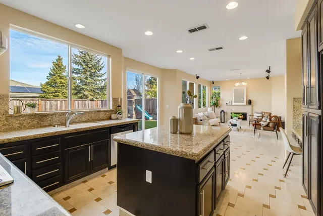 a kitchen with stainless steel appliances kitchen island granite countertop a refrigerator and a stove top oven