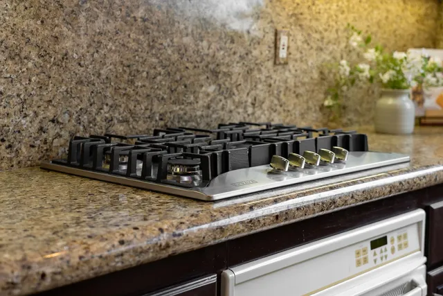 a kitchen with kitchen island granite countertop a sink a counter top space appliances and cabinets