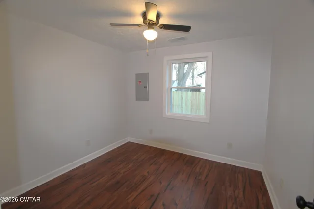 a view of empty room with wooden floor and fan