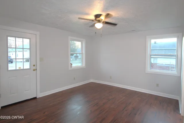 a view of an empty room with wooden floor and a window