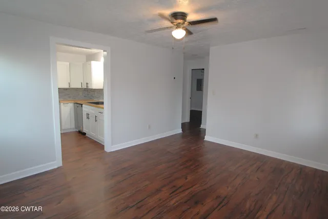 an empty room with wooden floor and ceiling fan