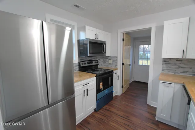 a kitchen with stainless steel appliances granite countertop a refrigerator a stove a sink and a microwave