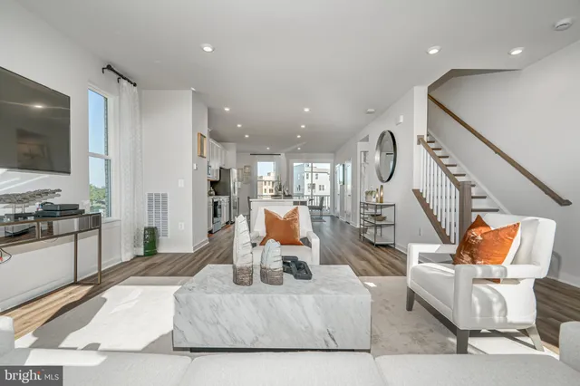 a living room with furniture kitchen view and a large window
