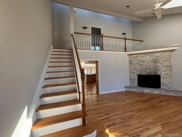 a view of an empty room with wooden floor fireplace and a window