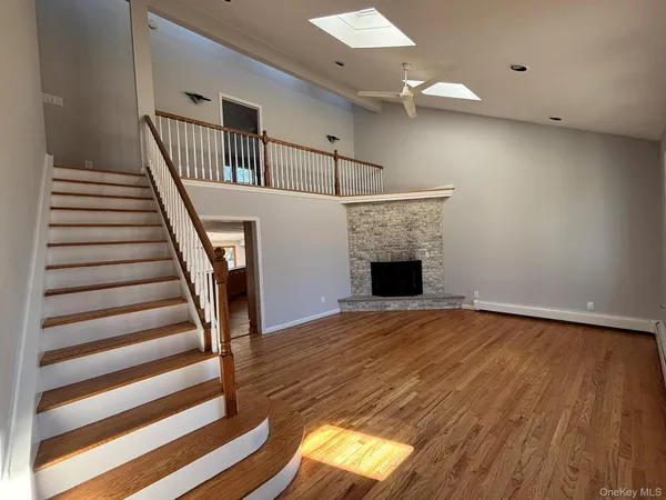 a view of an empty room with wooden floor and a fireplace
