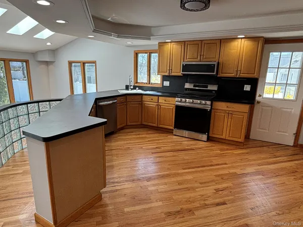 a kitchen with granite countertop a stove top oven a sink dishwasher and cabinets with wooden floor