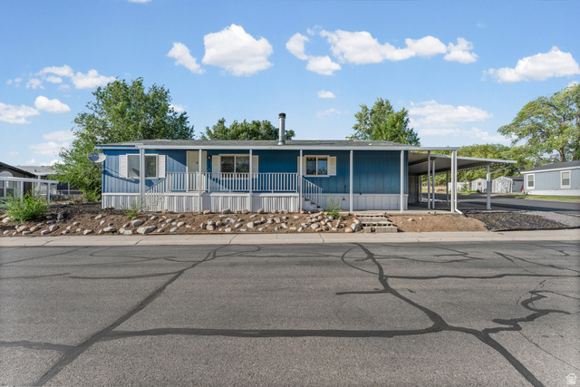 312 Harriger Way Layton, UT 84041 - Photo 28 of 36 Blue siding exterior with white trim, covered front porch with white railing, and an attached carport