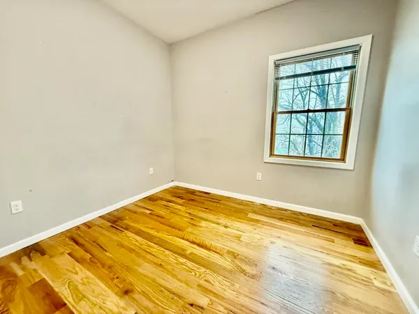 an empty room with wooden floor and a window