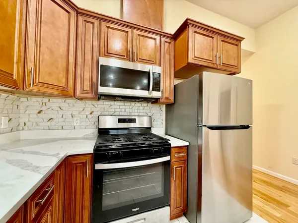 a kitchen with stainless steel appliances granite countertop a refrigerator a stove a sink and a microwave