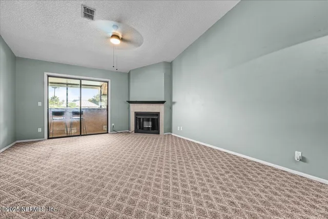 an empty room with windows and fireplace