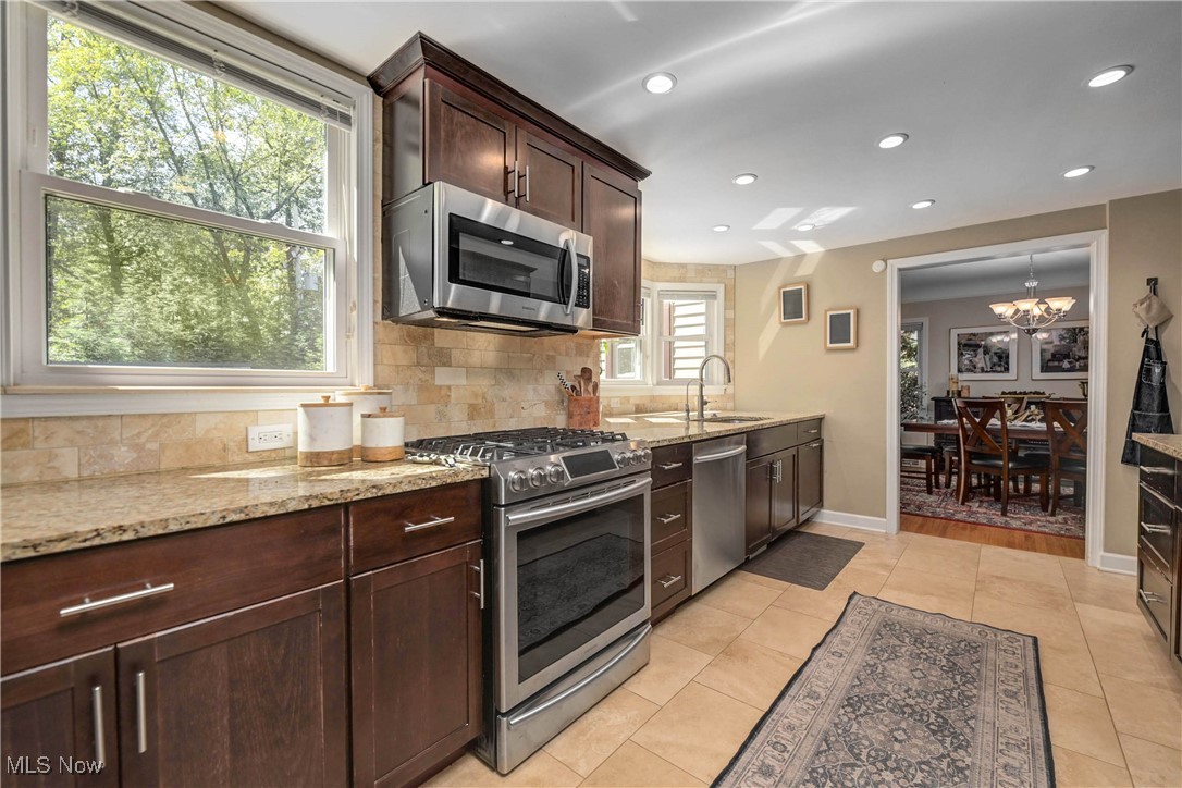 4022 Hillbrook Road Cleveland, OH 44118 - Photo 13 of 49 Kitchen featuring stainless steel appliances, dark brown cabinets, light stone counters, recessed lighting, and backsplash