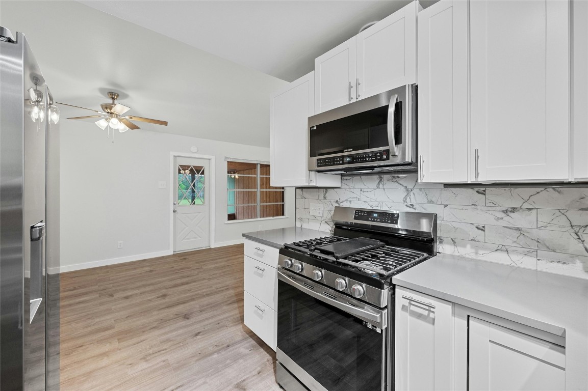 4906 Sylvandale Drive Austin, TX 78745 - Photo 11 of 28 a kitchen with stainless steel appliances a stove a microwave and cabinets