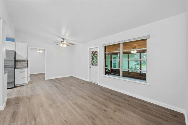a view of an empty room with a window and wooden floor