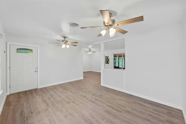 an empty room with wooden floor chandelier fan and closet area