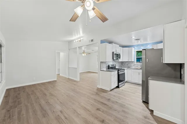 a large kitchen with cabinets wooden floor and stainless steel appliances