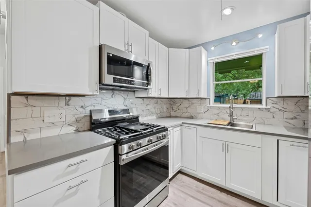 a kitchen with stainless steel appliances granite countertop white cabinets granite counter tops and a window