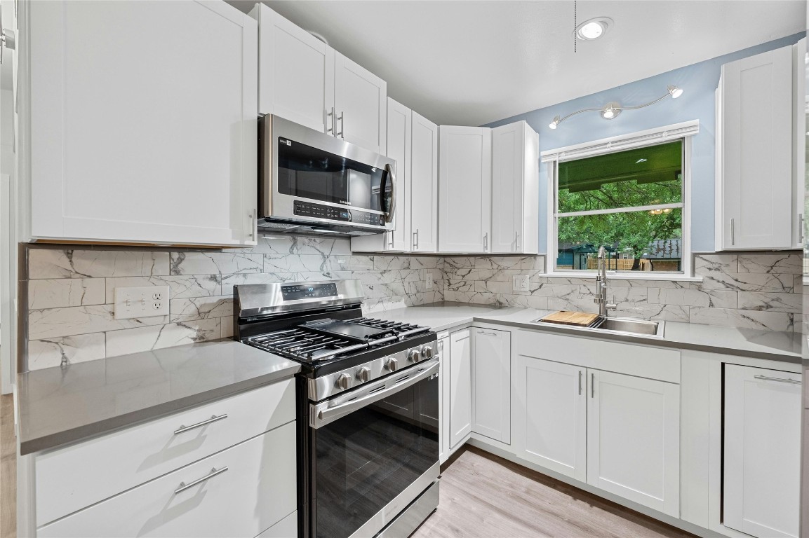 4906 Sylvandale Drive Austin, TX 78745 - Photo 10 of 28 a kitchen with stainless steel appliances granite countertop white cabinets granite counter tops and a window