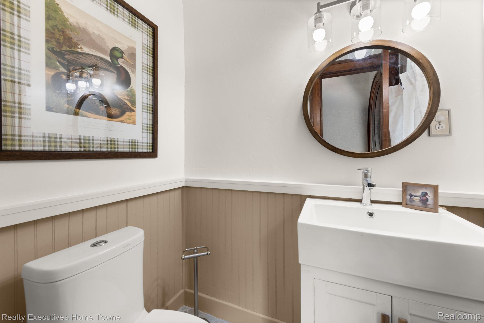 8308 Lakeshore Road Fort Gratiot, MI 48059 - Photo 32 of 79 White toilet with a corner-mounted vanity, featuring a white vessel sink and a chrome faucet