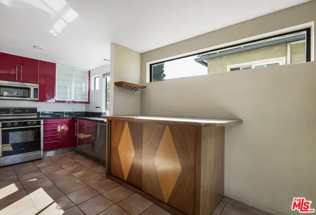 a kitchen with stainless steel appliances granite countertop a stove sink and red cabinets