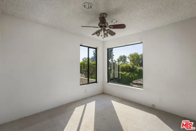 an empty room with a ceiling fan and a carpet