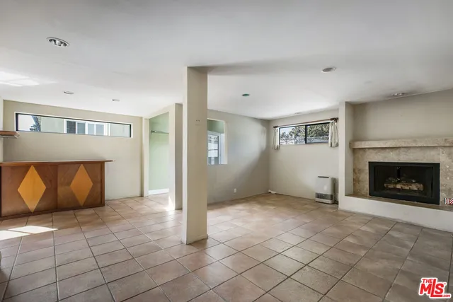 an empty room with windows and fireplace