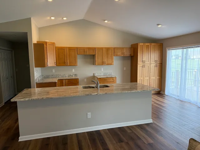 a large kitchen with stainless steel appliances a large counter top a sink and a refrigerator