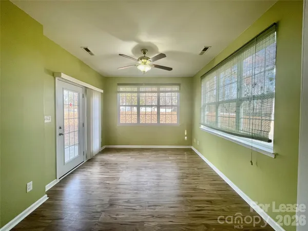 a view of an empty room with a window and wooden floor