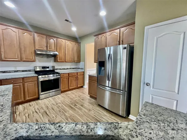 a kitchen with granite countertop wooden floors stainless steel appliances and a window