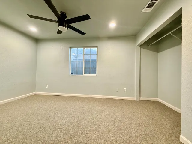 an empty room with windows and fan