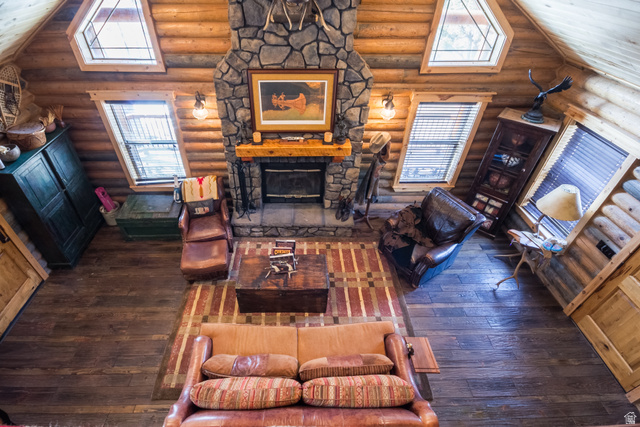18906 North Canyon Road Whiterocks, UT 84085 - Photo 35 of 65 Living room with dark wood-style floors, vaulted ceiling, a stone fireplace, and rustic walls