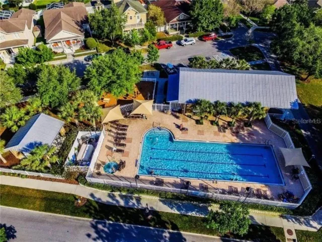 an aerial view of a swimming pool with a yard and trees