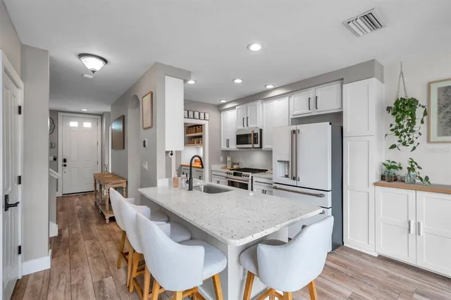 a kitchen with stainless steel appliances granite countertop a dining table chairs refrigerator and microwave