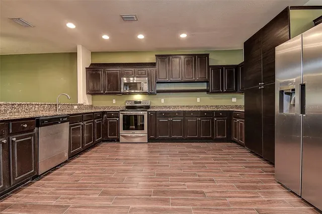 a large kitchen with stainless steel appliances granite countertop a stove top oven a sink and dishwasher