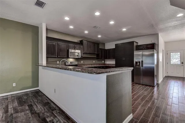 a kitchen with stainless steel appliances granite countertop a refrigerator and a stove top oven