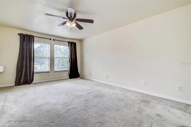 an empty room with windows and ceiling fan