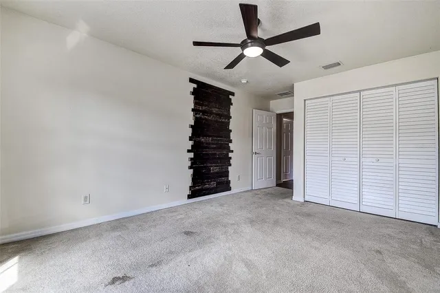 an empty room with a ceiling fan and window