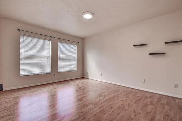 a view of an empty room with wooden floor and a window