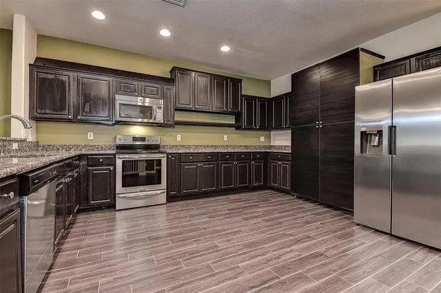 a kitchen with stainless steel appliances granite countertop a large counter top a stove and a refrigerator