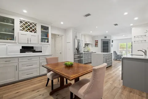 a kitchen with white cabinets stainless steel appliances and dining table