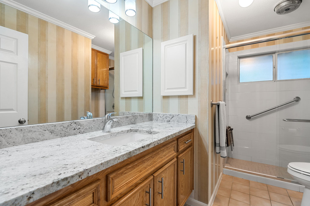 1709 Crested Butte Drive Austin, TX 78746 - Photo 29 of 40 a bathroom with a granite countertop sink toilet and shower
